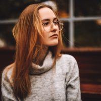 pensive woman sitting wearing eyeglasses looking far away