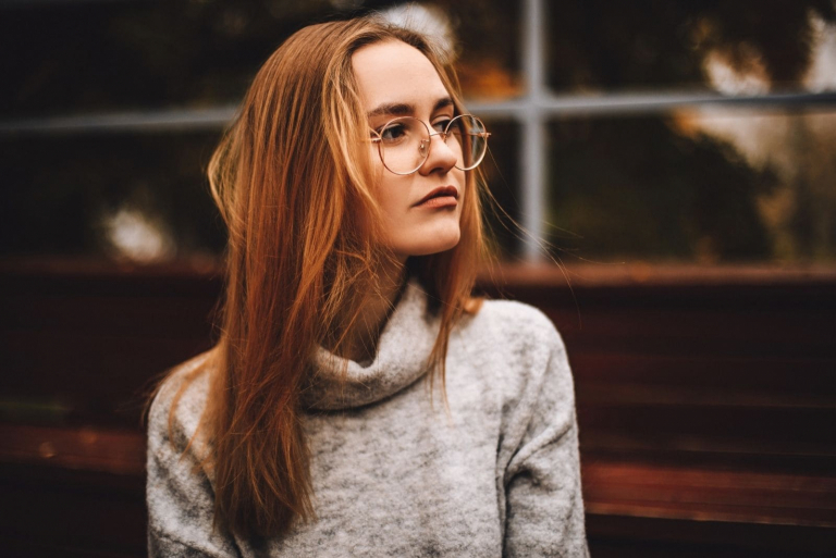 pensive woman sitting wearing eyeglasses looking far away