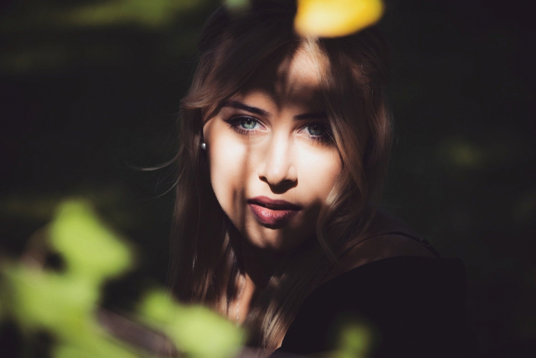 blonde woman with blue eyes standing near tree