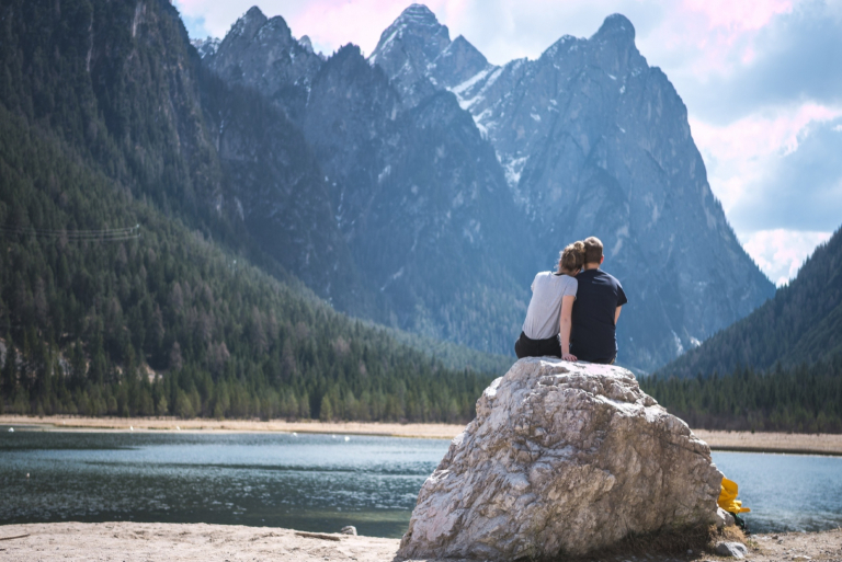 man and woman sitting on rock looking at mountain