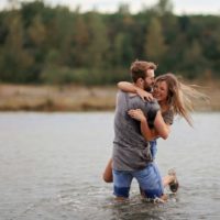 hombre feliz abrazando a una mujer mientras está de pie en el agua