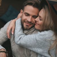 sweet woman hugging a man closing their eyes while sitting