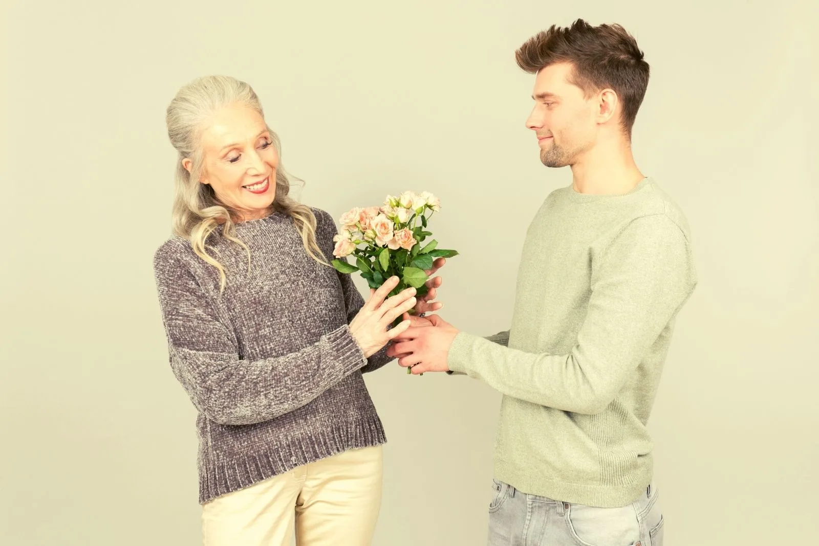 age gap love of a younger man giving flower to a mature woman