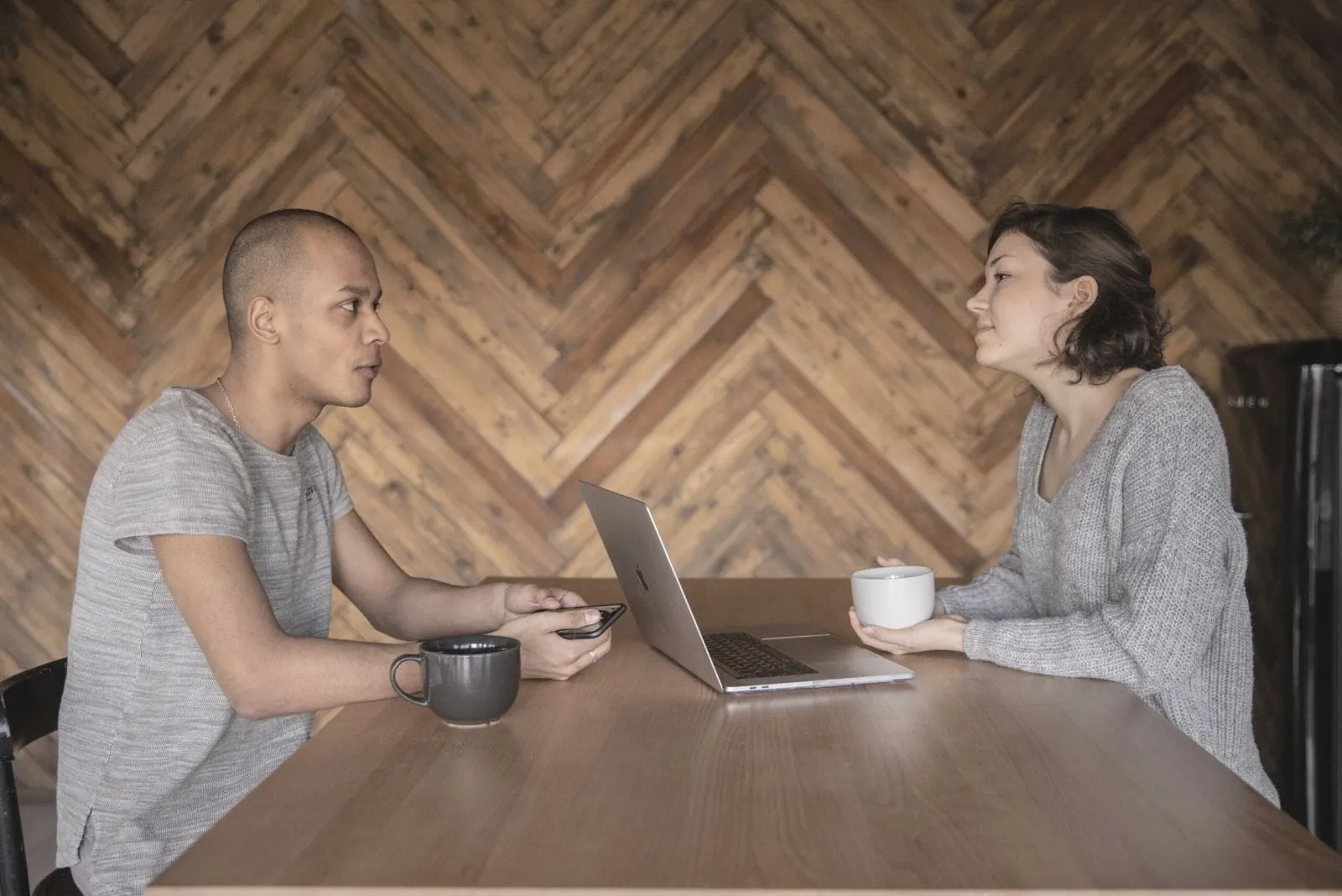 asian couple talking inside a cafe with a laptop and coffe at the table