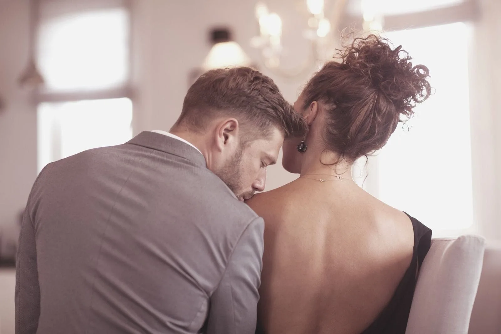 back view of an elegant couple sitting with the man kissing on the woman's shoulder