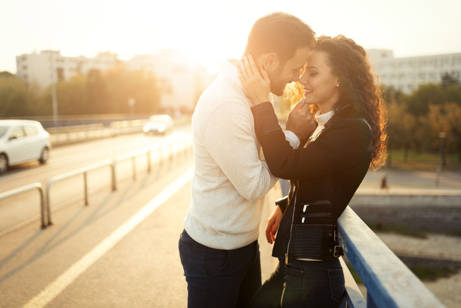 bella coppia che si bacia appoggiata alla ringhiera della strada durante il tramonto