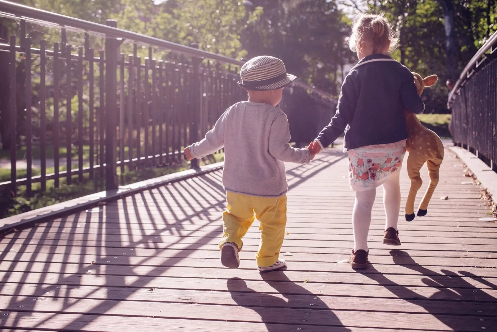 boy and girl holding hands while walking on bridge