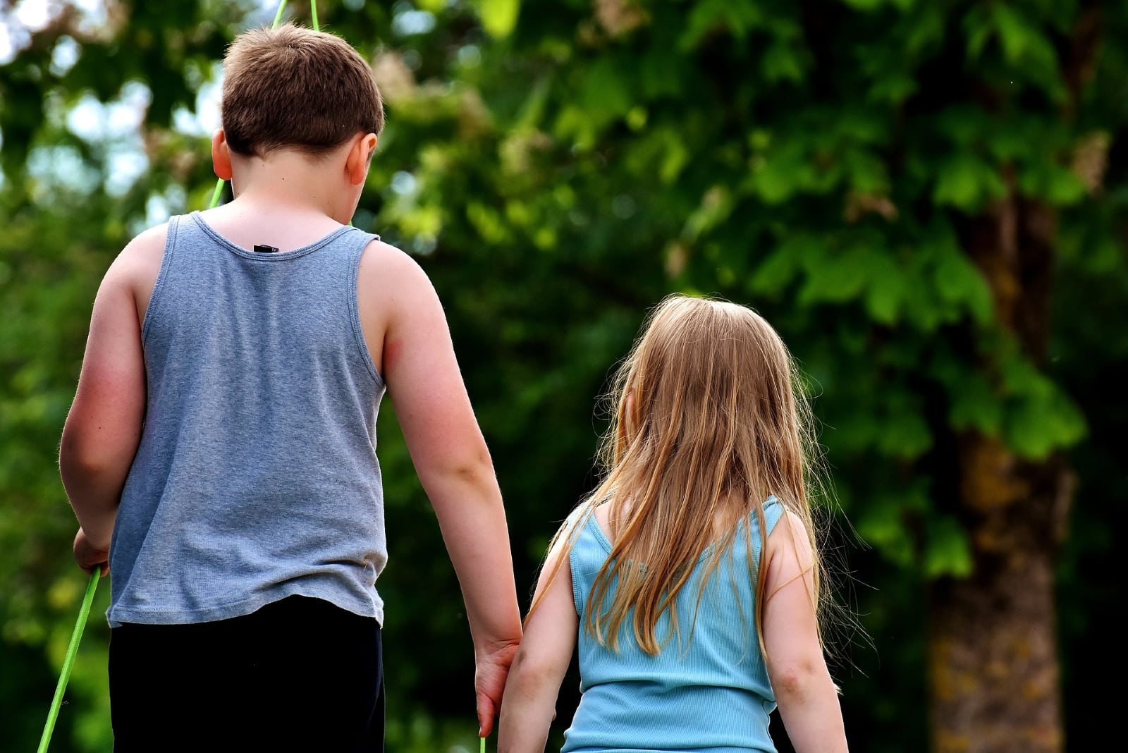 brother holding sister's arm while walking outdoor