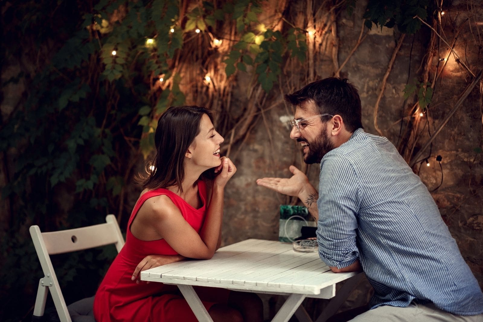 Coppia allegra che parla mentre aspetta il cibo durante il loro appuntamento