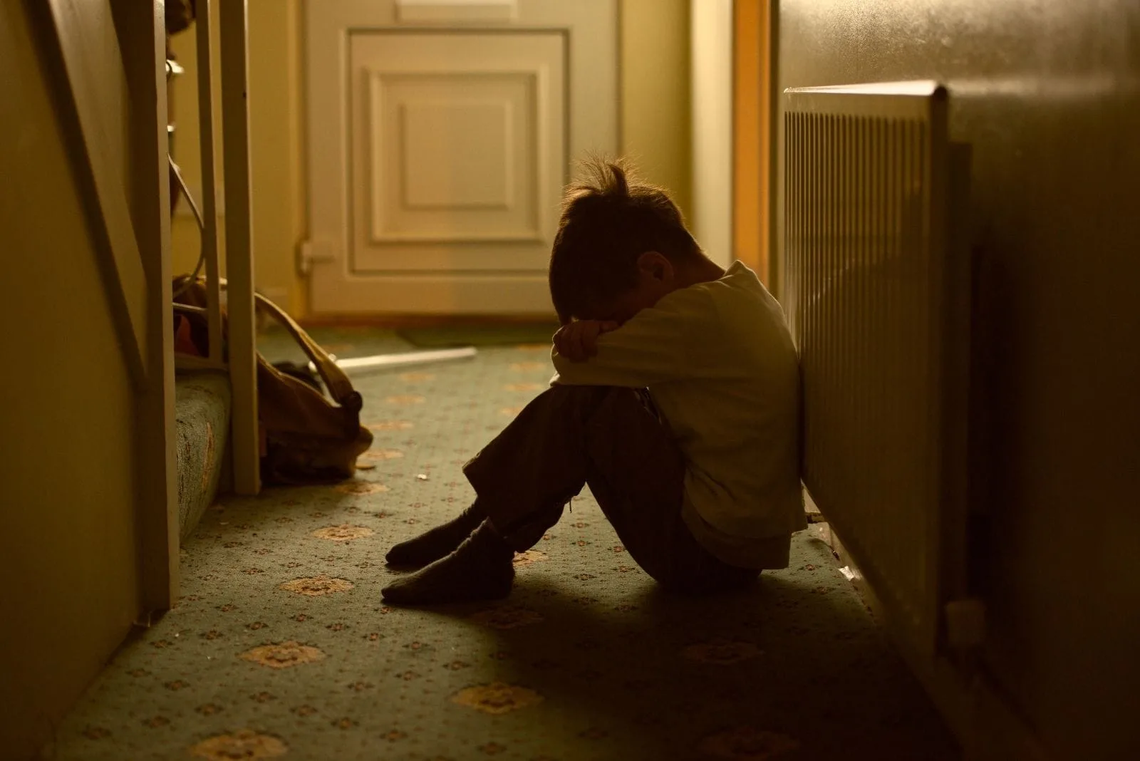 child victim of maltreatment sitting on the dark room crying