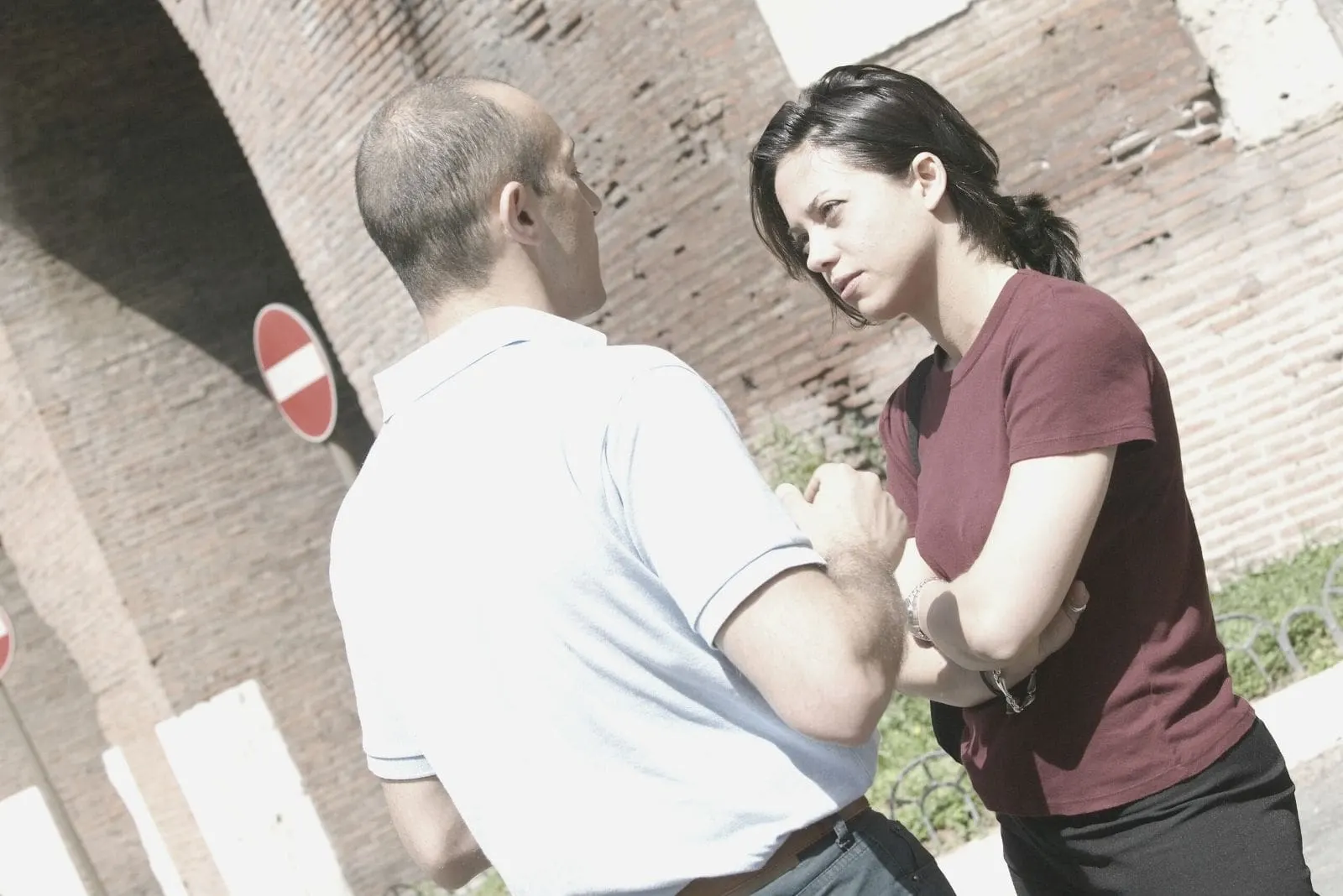 couple arguing outdoors standing near a brick wall building