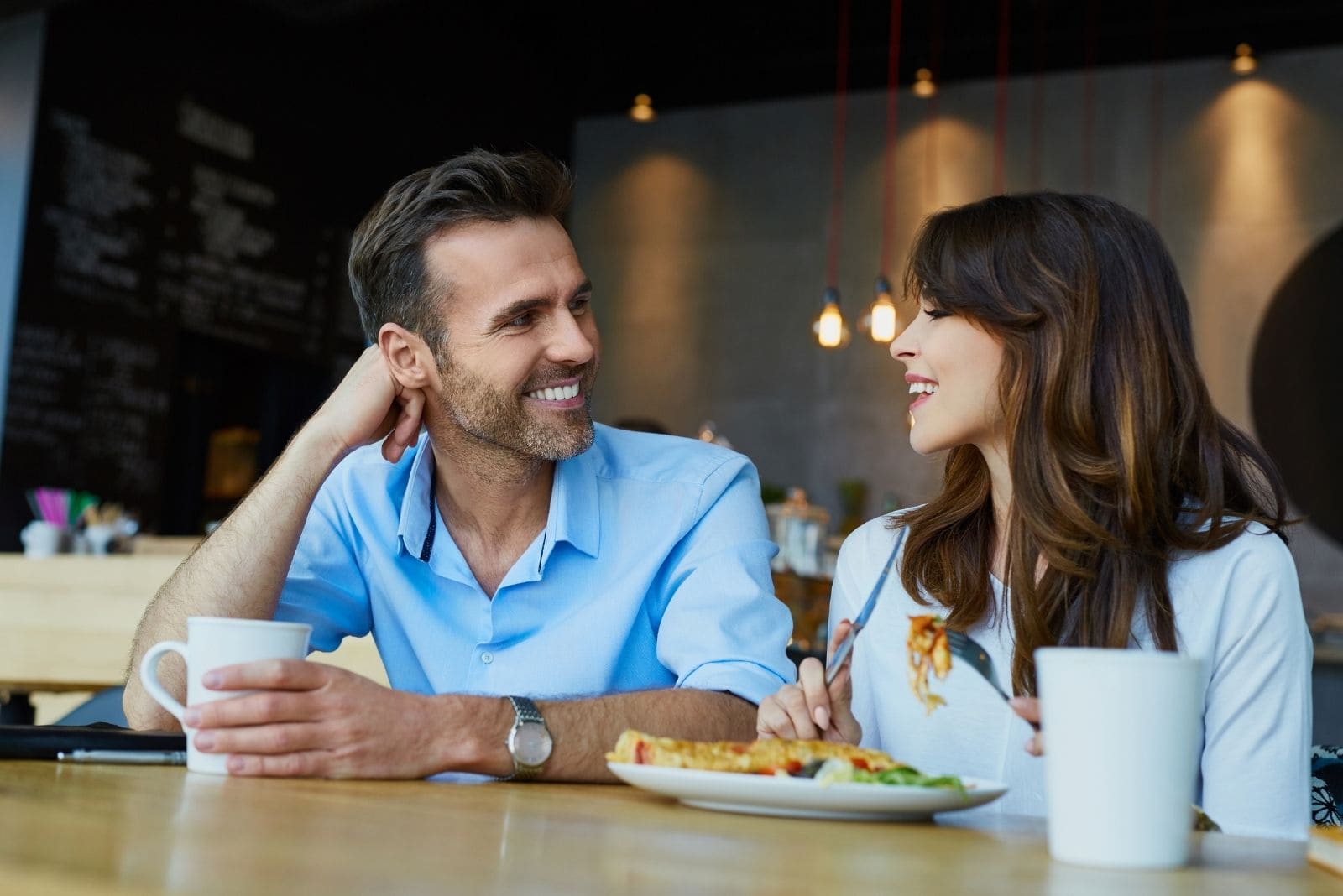 casal num café a conversar enquanto come 