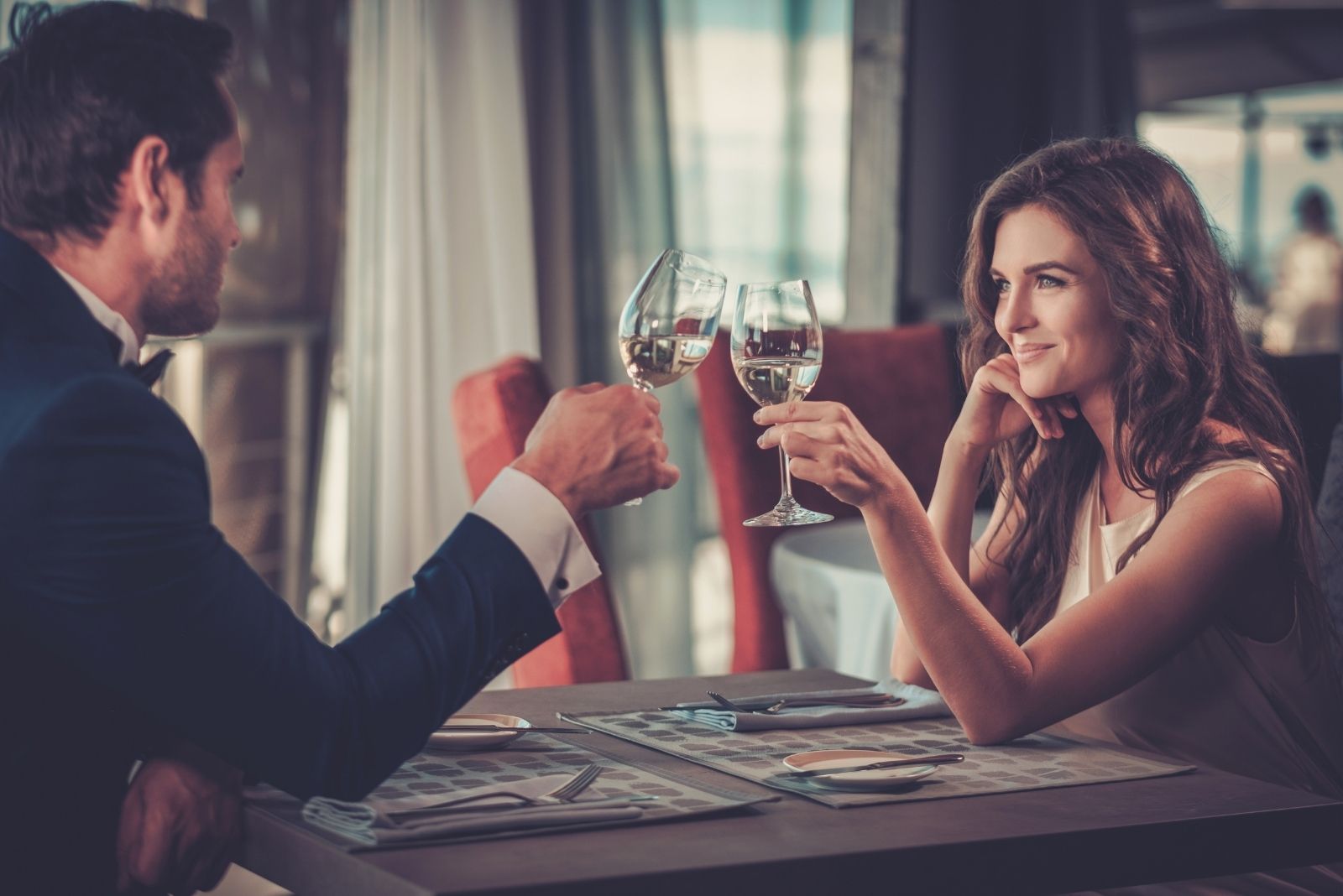 couple clinking wine glasses during their dinner date inside restaurant