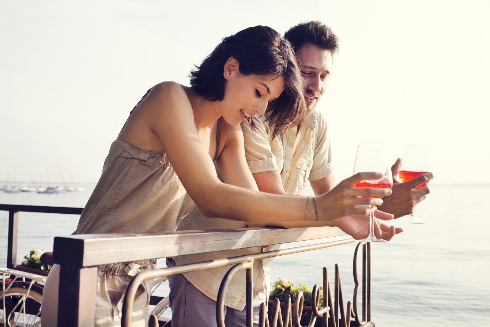 couple drinking wine while standing at an outdoor restaurant near the sea