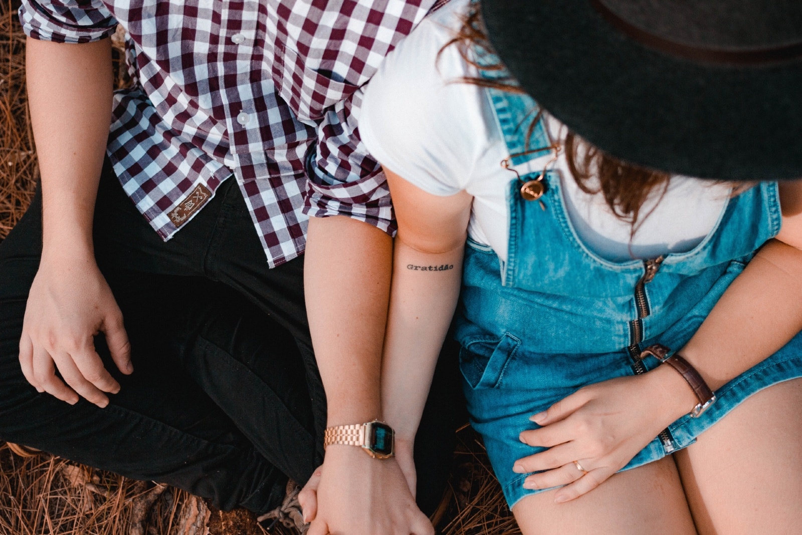 man and woman holding hands while sitting on ground