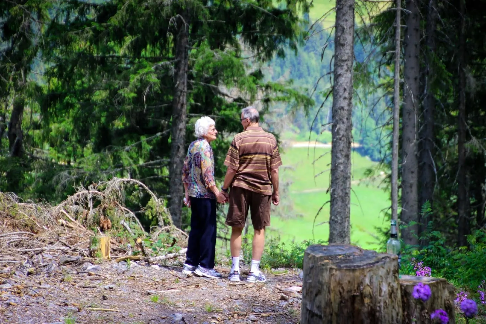 man and woman holding hands while standing in forest