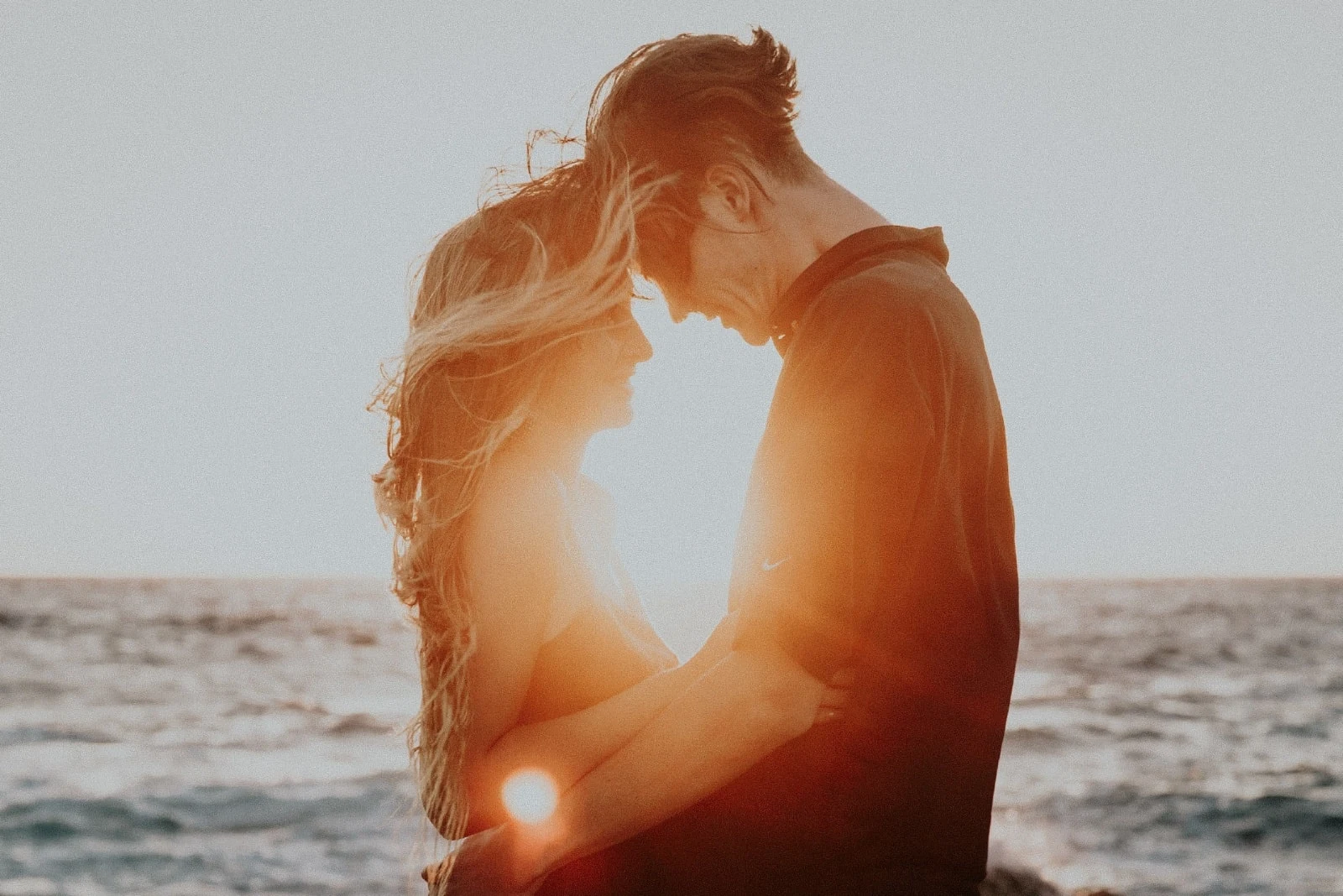 man and woman hugging while standing near sea
