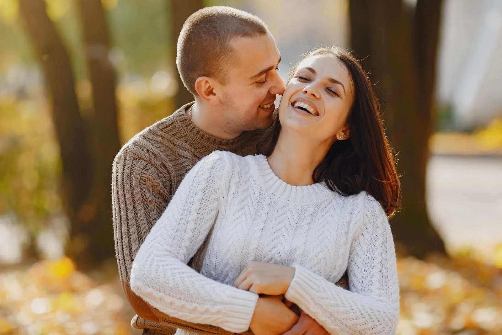 man and woman in sweaters hugging on street