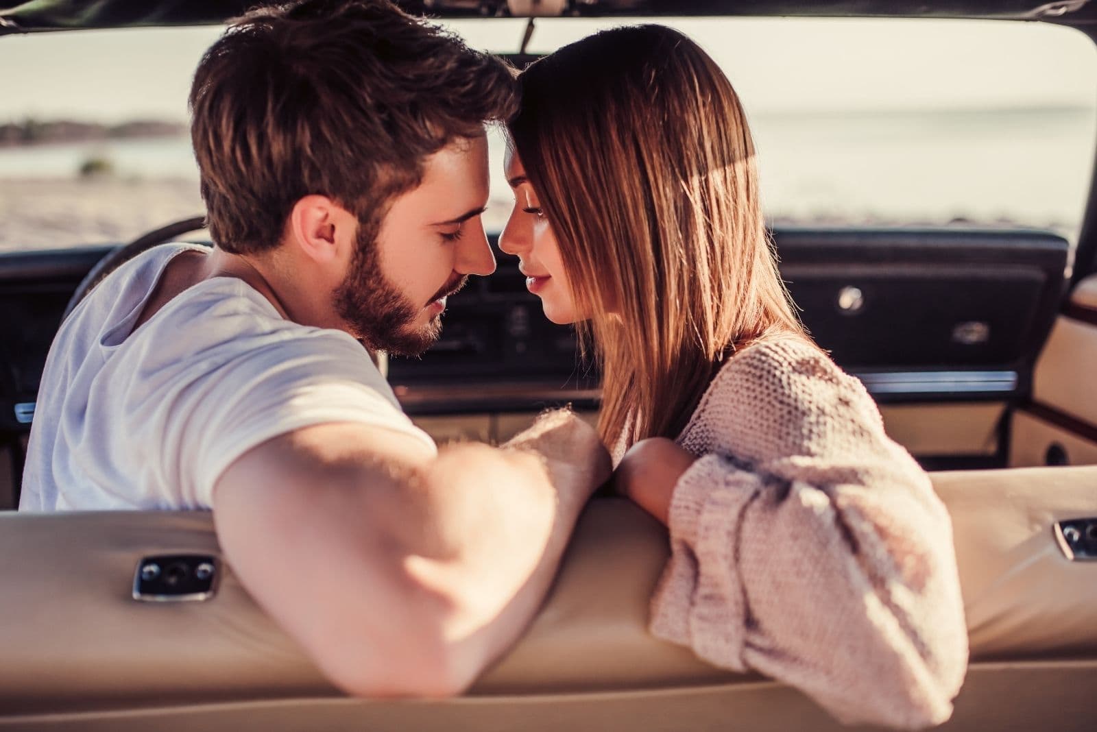 casal num carro retro apaixonado prestes a beijar-se sentado 