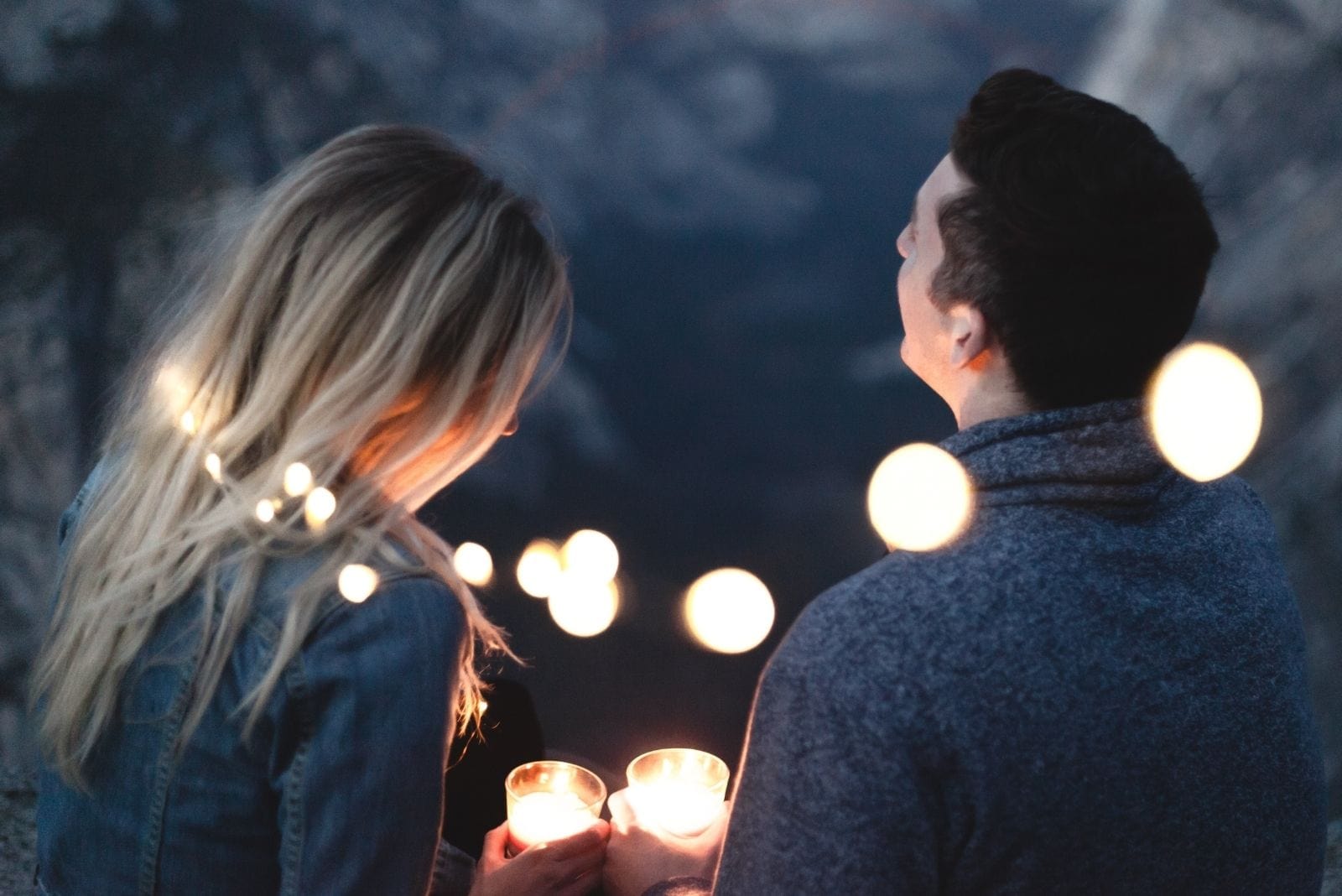 casal apaixonado com luzes à sua volta segurando velas