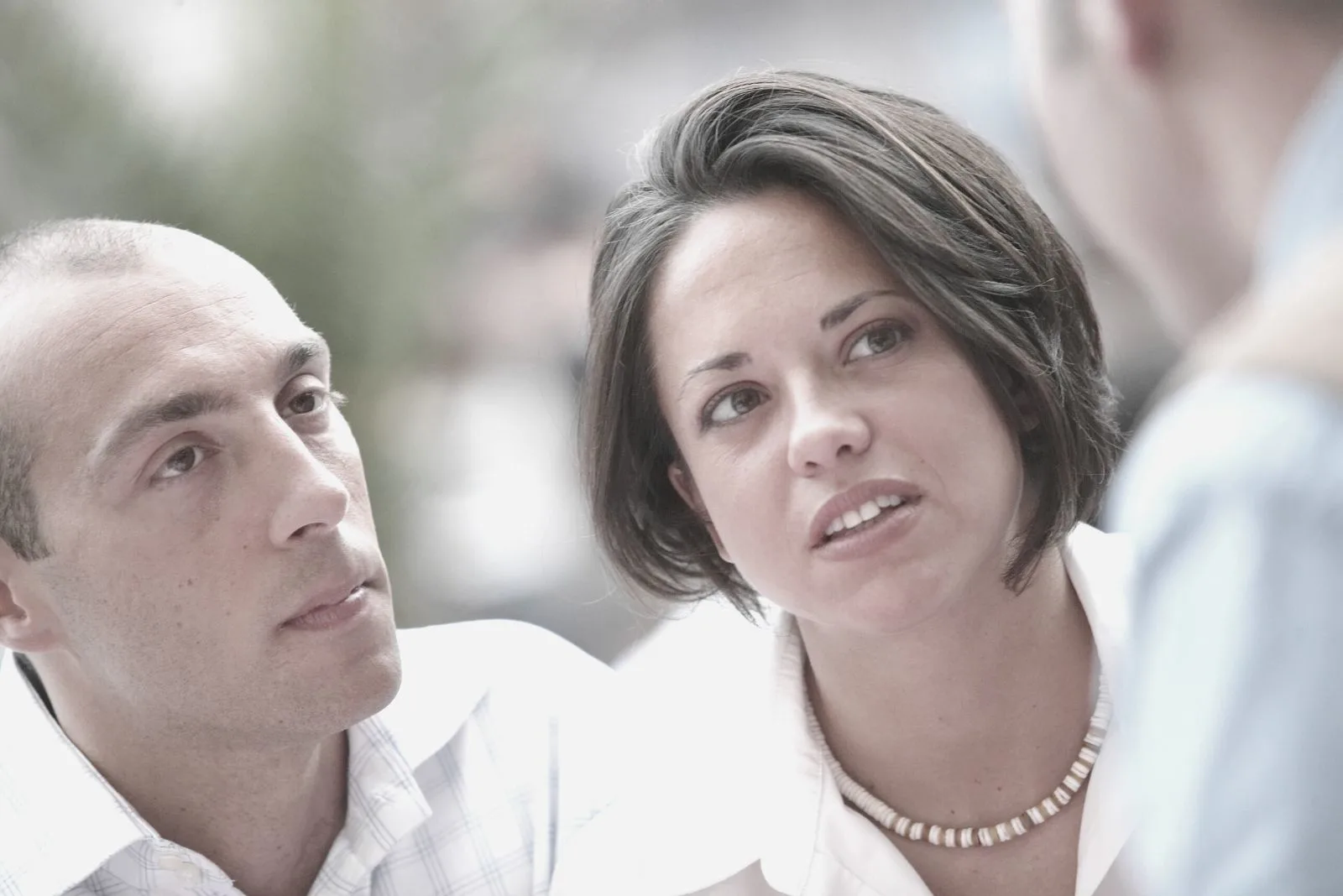 couple in serious conversation with another person in focus