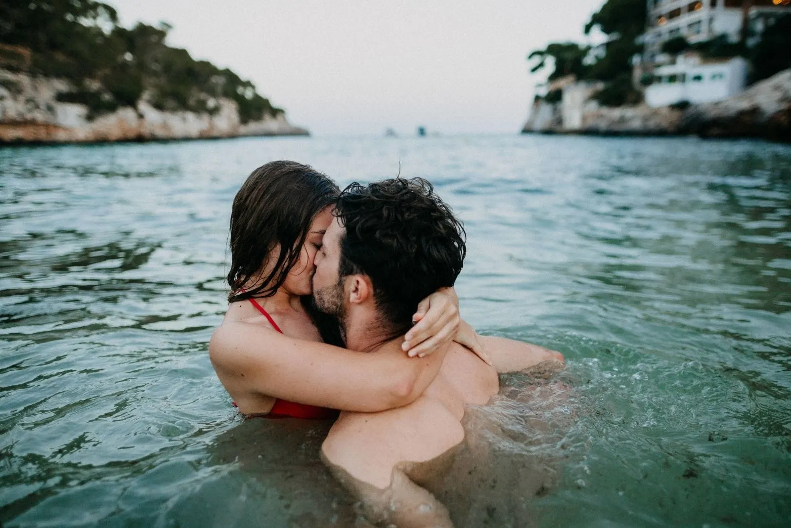 couple in the water kissing passionately wearing swimwear