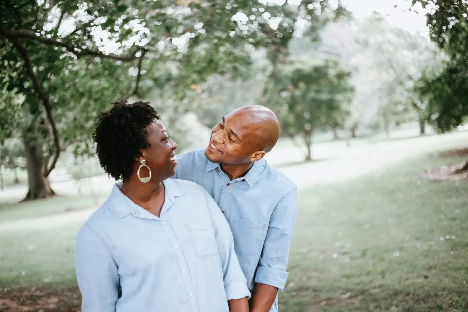 man and woman making eye contact while standing near tree