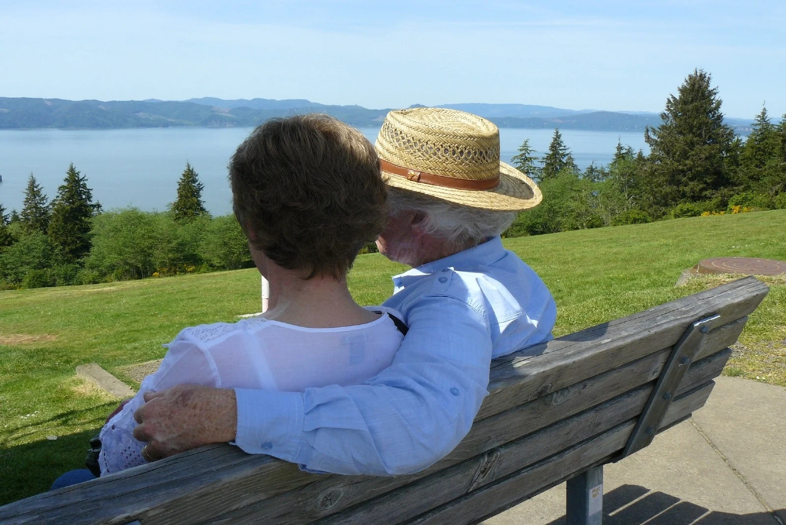 man with hat and woman hugging while sitting on bench