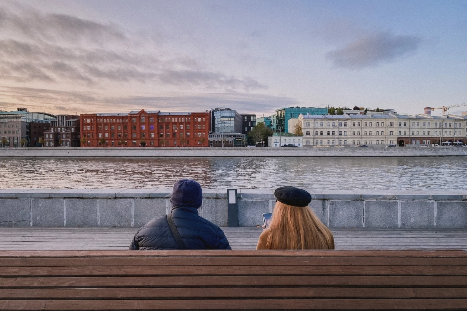 man and woman sitting on bench looking at water