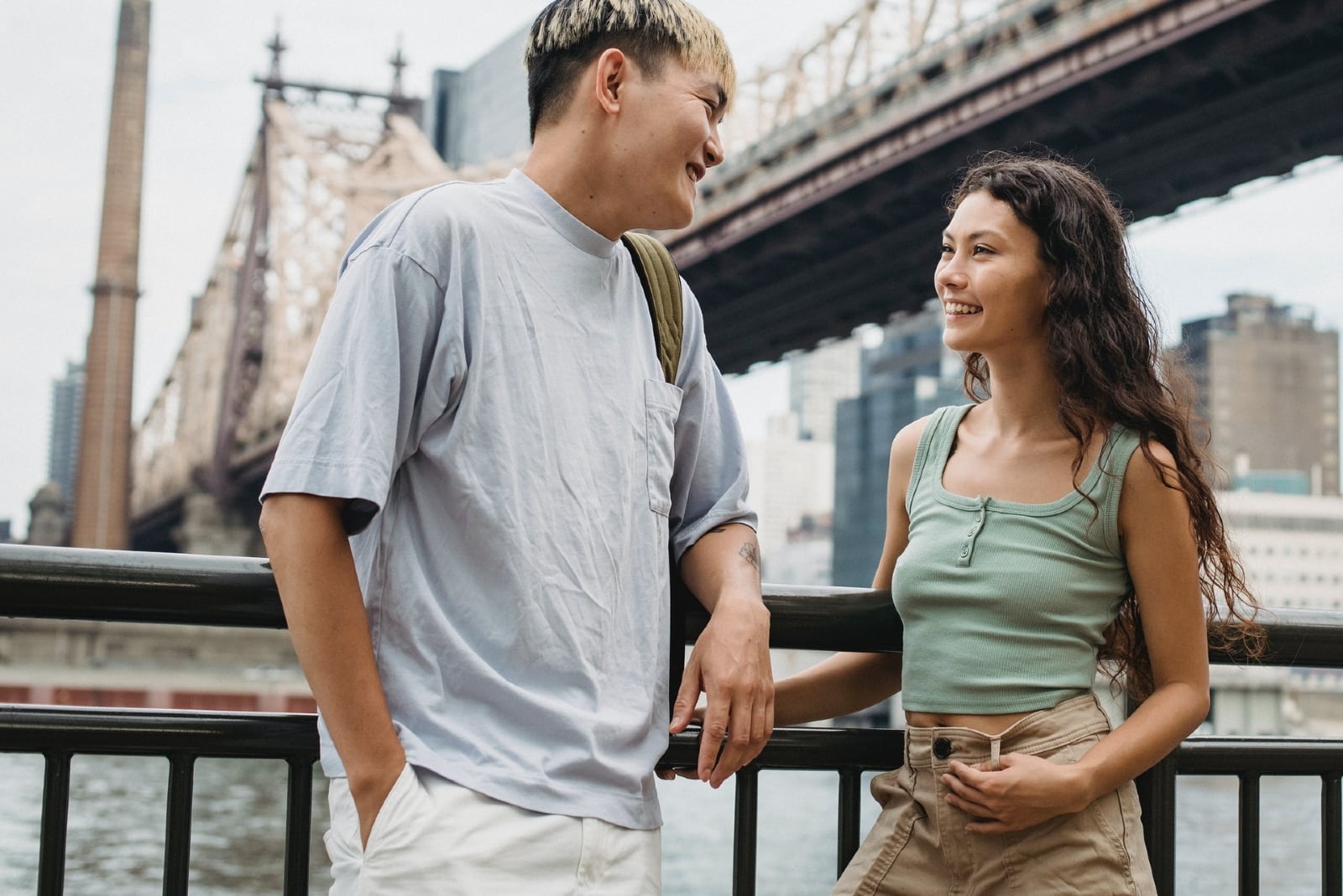 man and woman talking while standing near bridge