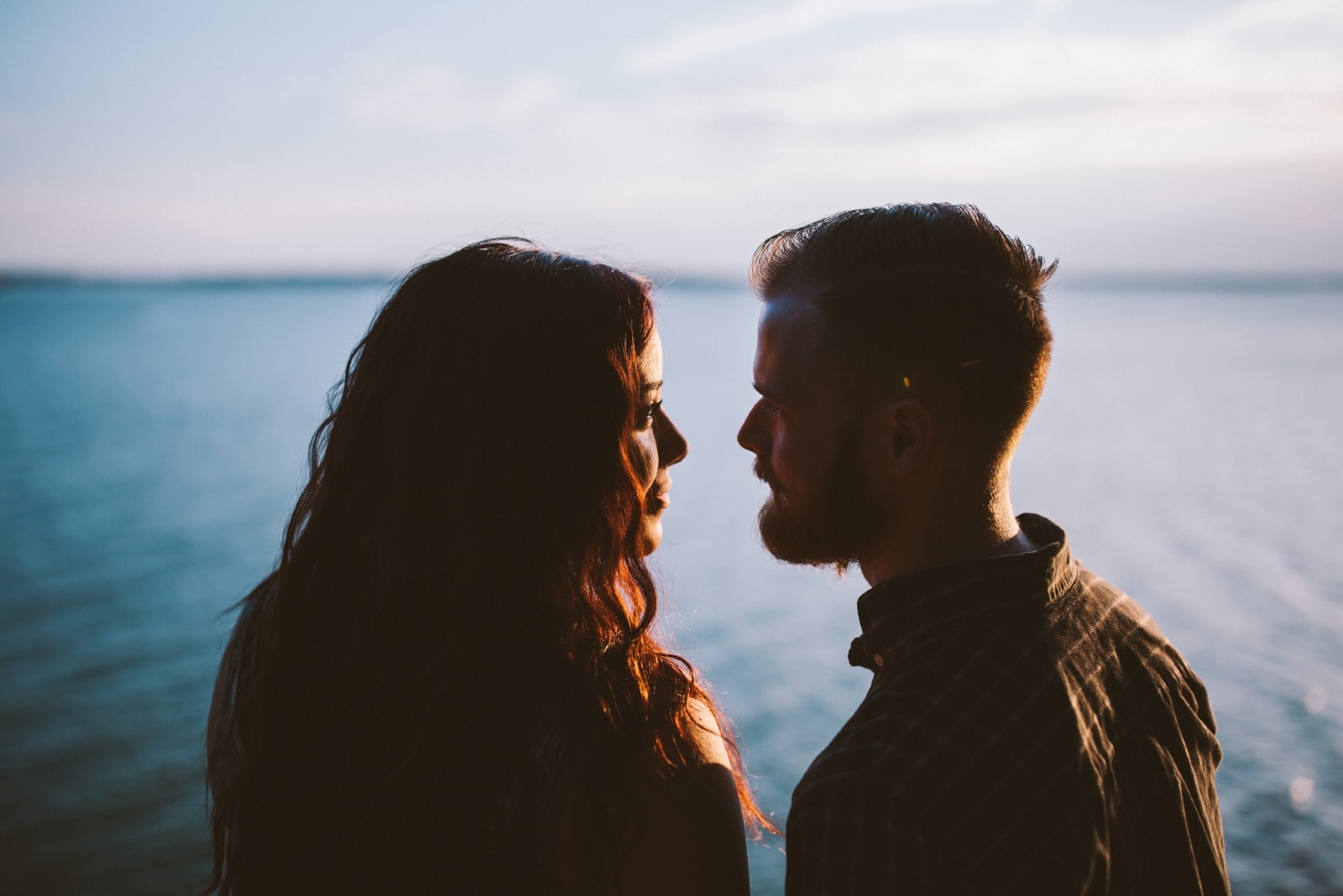 un hombre y una mujer se miran a los ojos cerca del agua