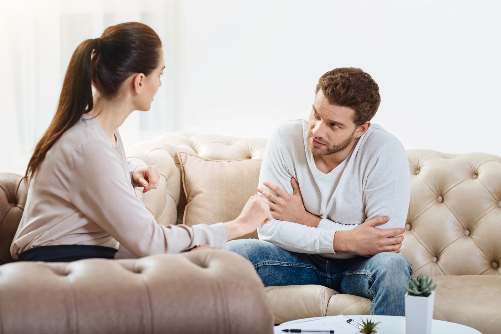 man and woman talking while sitting on sofa