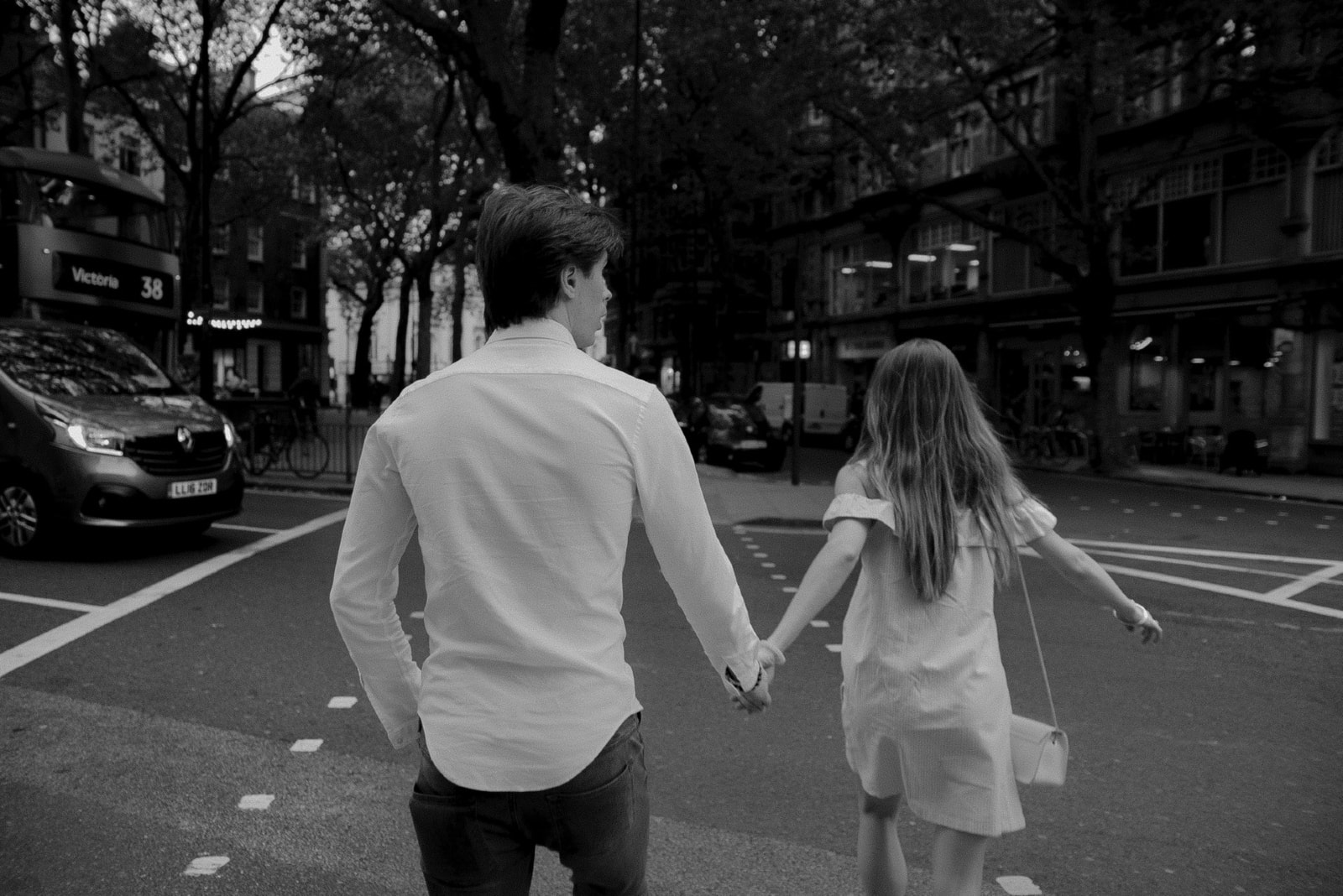man and woman holding hands while walking on the street