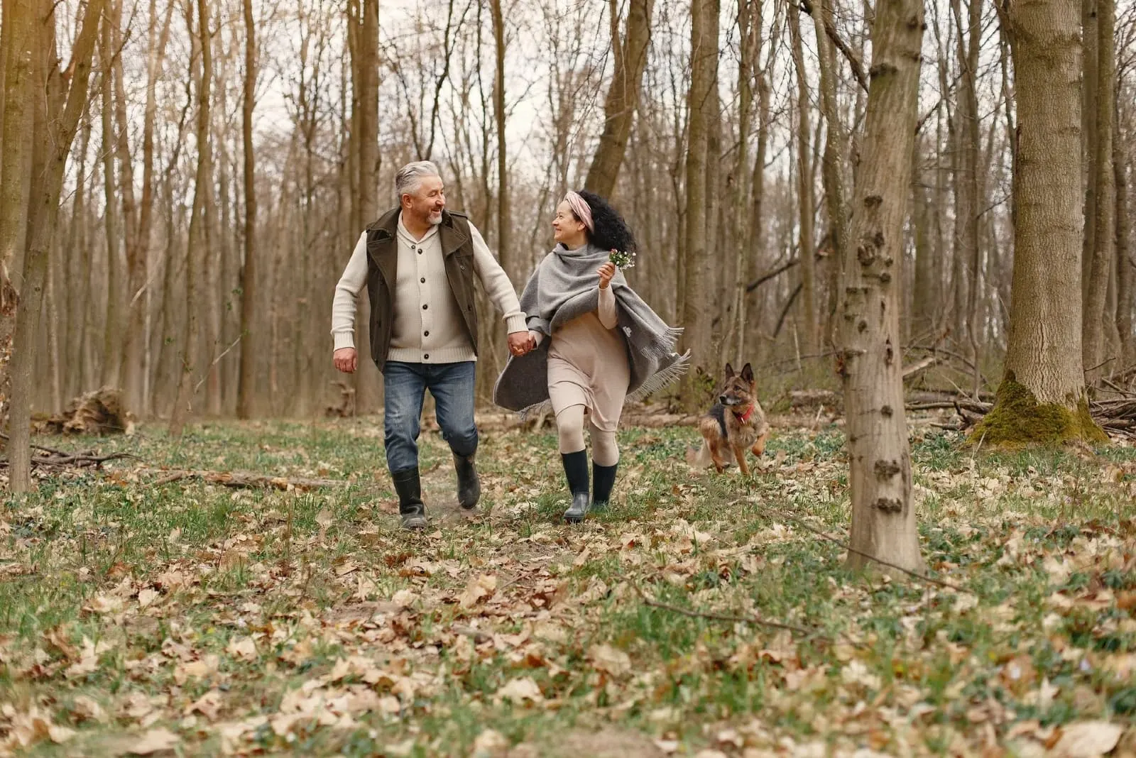 man and woman walking in forest with dog