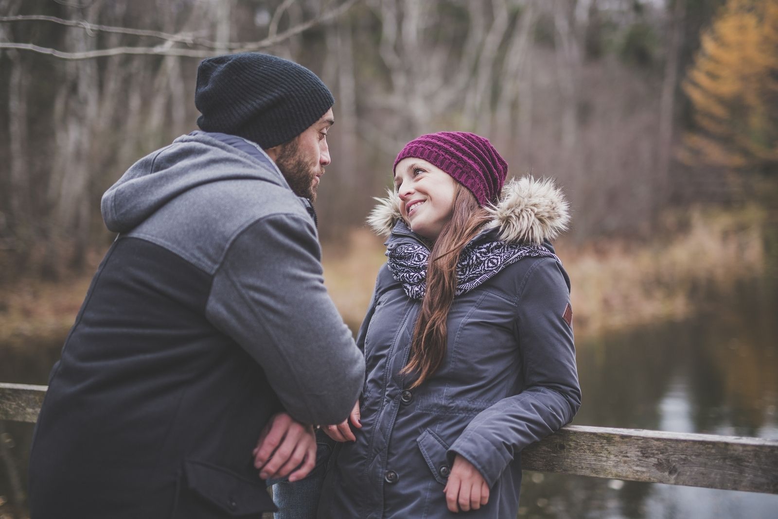 couple wearing jackets outdoors talking sweetly during autumn season