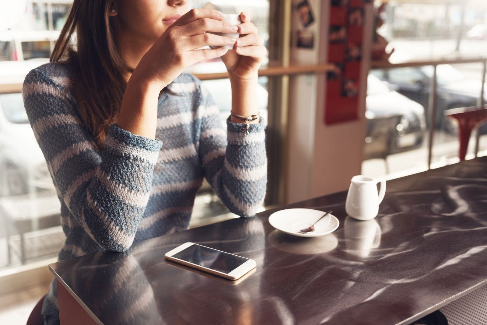 cropped photo of a woman sitting in a cafe thinking deeply and drinking coffee