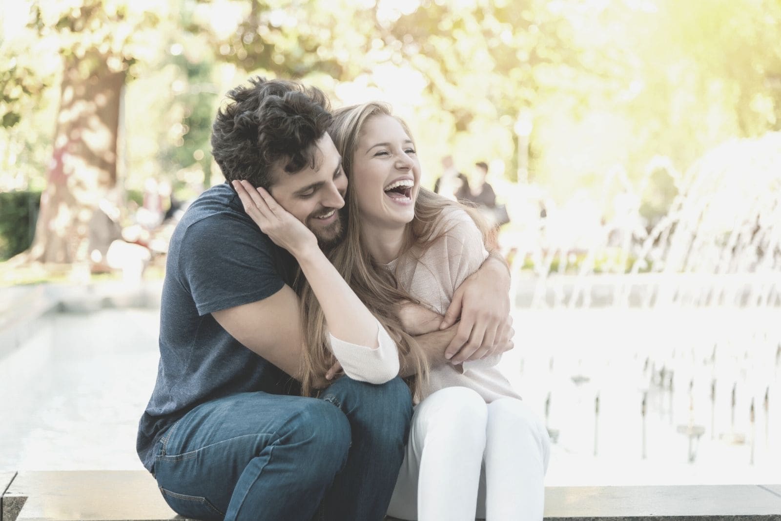 coppia felice nel parco seduta e abbracciata vicino alla fontana