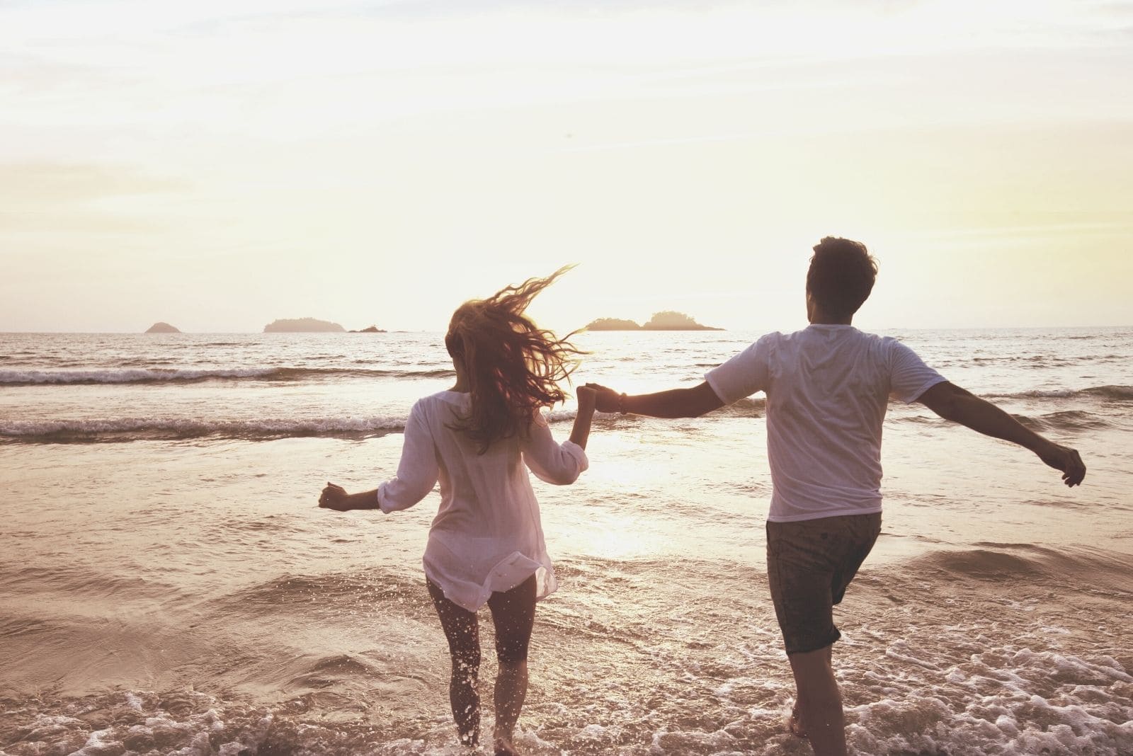 feliz pareja en luna de miel disfrutando en la playa corriendo a las aguas