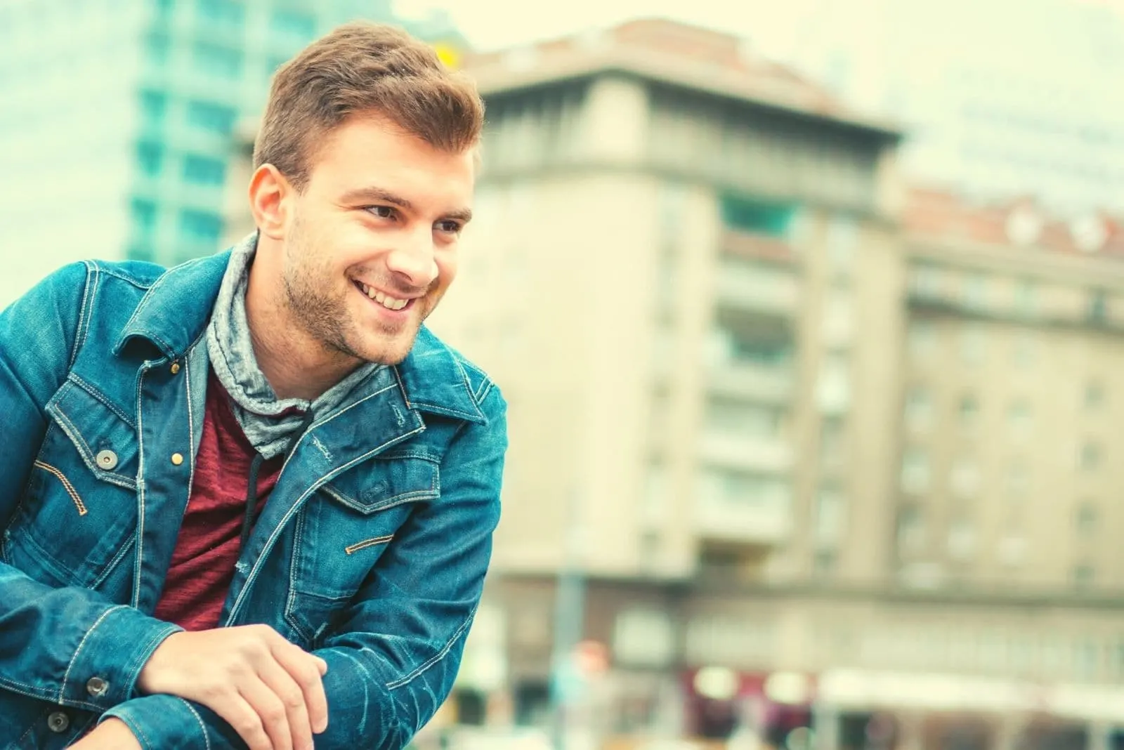 happy man smiling outdoors wearing denim jacket