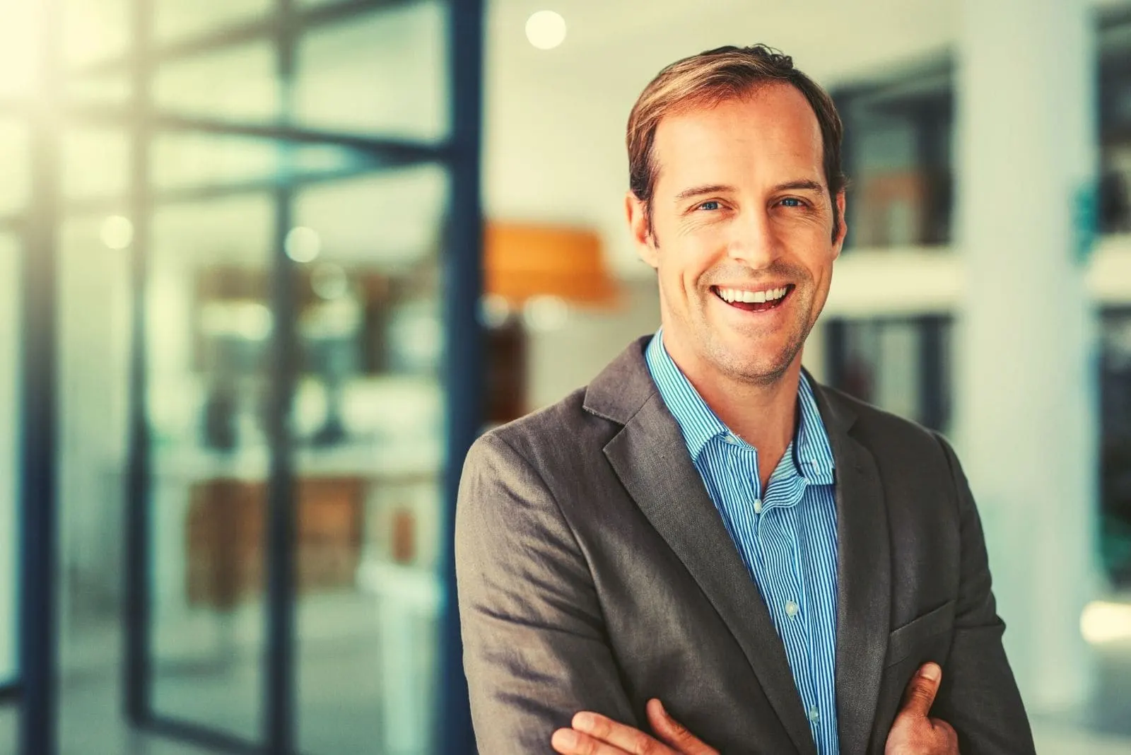 happy young businessman standing in the modern office and smiling