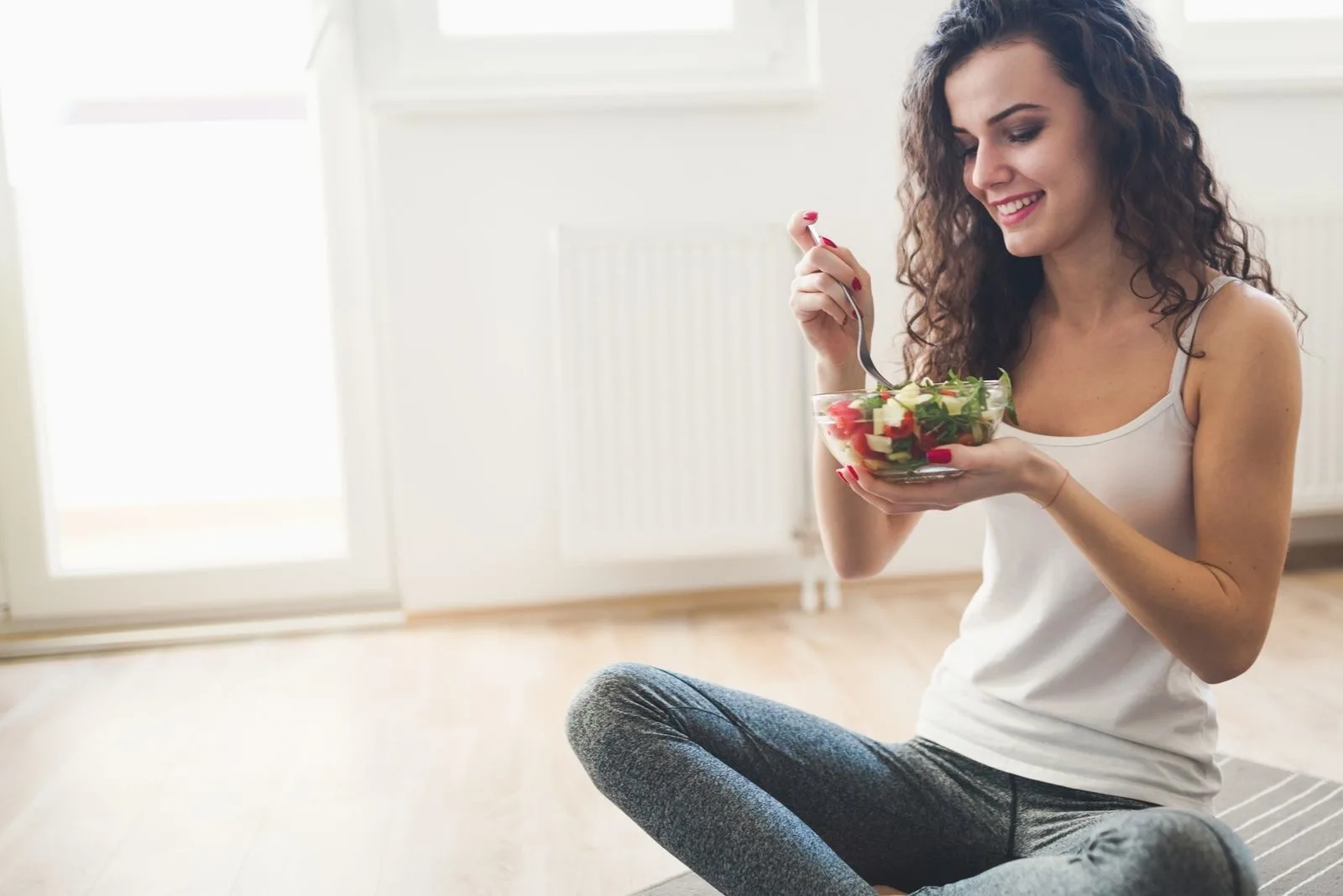healthy lifestyle of a young woman eating healthy foods while squatting on the floor