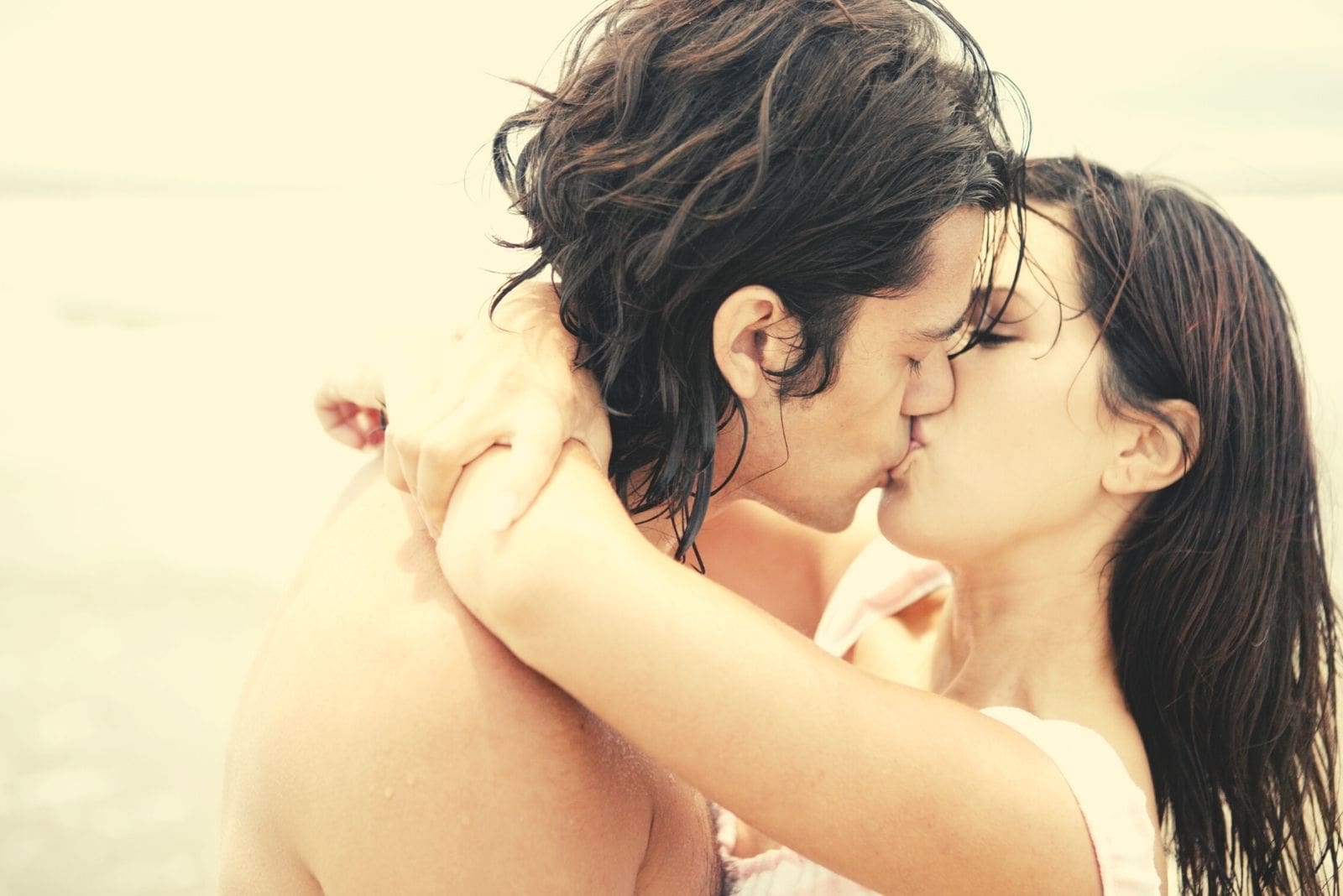 coppia ispanica che si bacia all'aperto con le braccia della donna intorno alle spalle del ragazzo