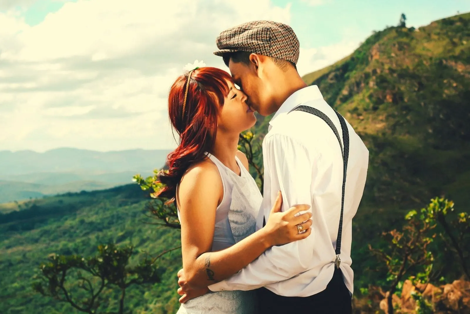 kissing couple standing in the mountains during the day