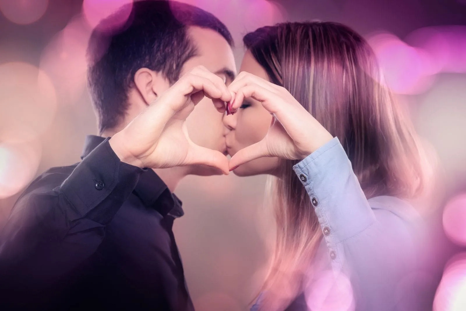 kissing young couple making a heart shape with bubble of colors around