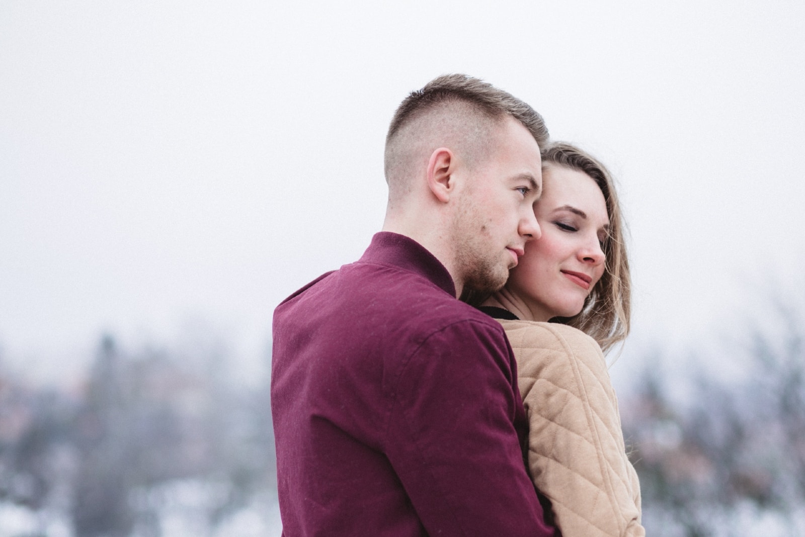man hugging woman while standing outdoor in winter