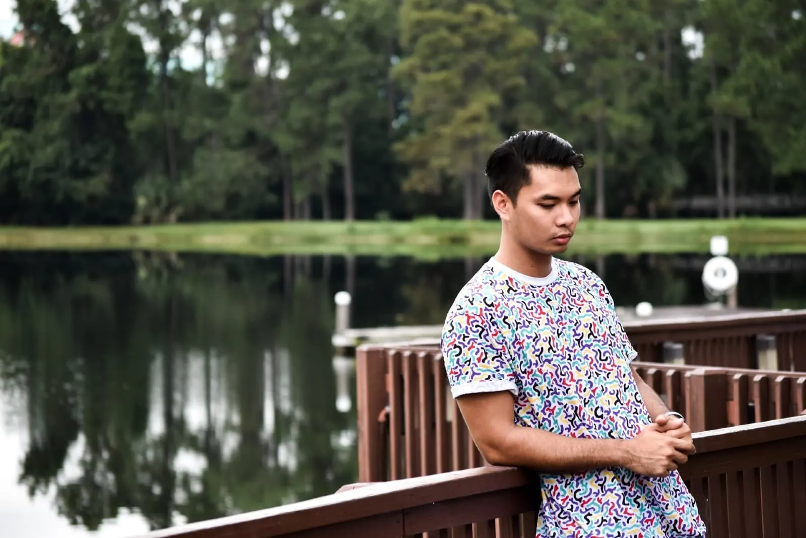 man leaning on wooden fence while standing near water