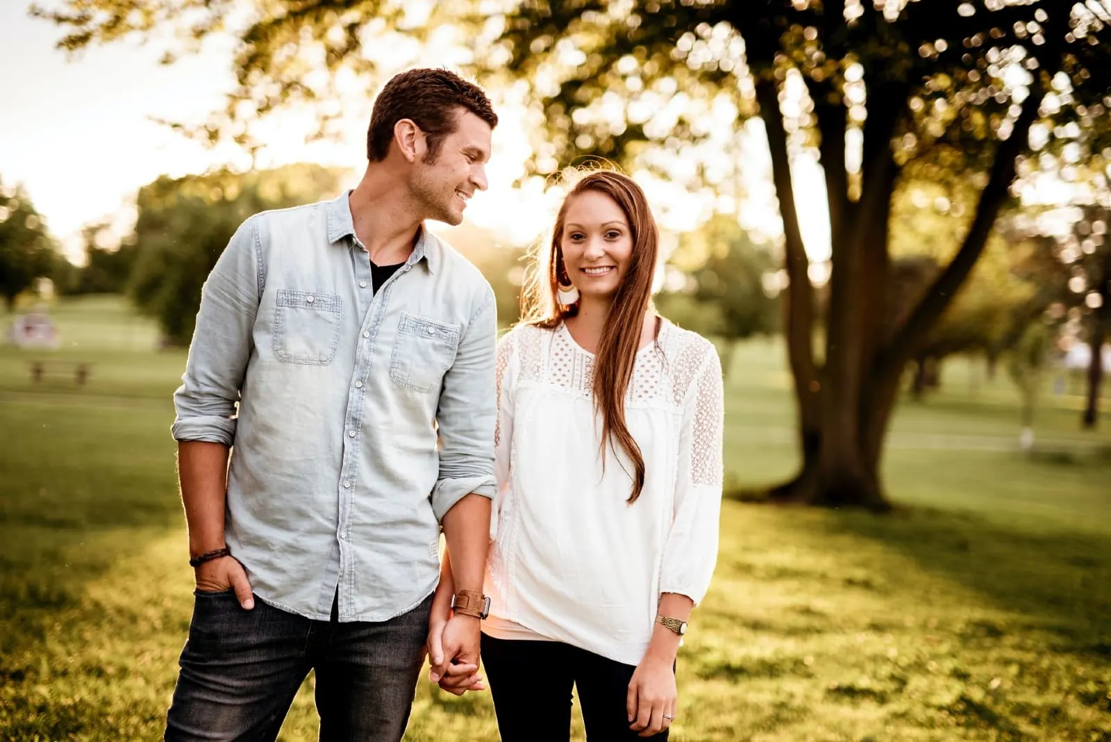 man looking at woman while standing near tree