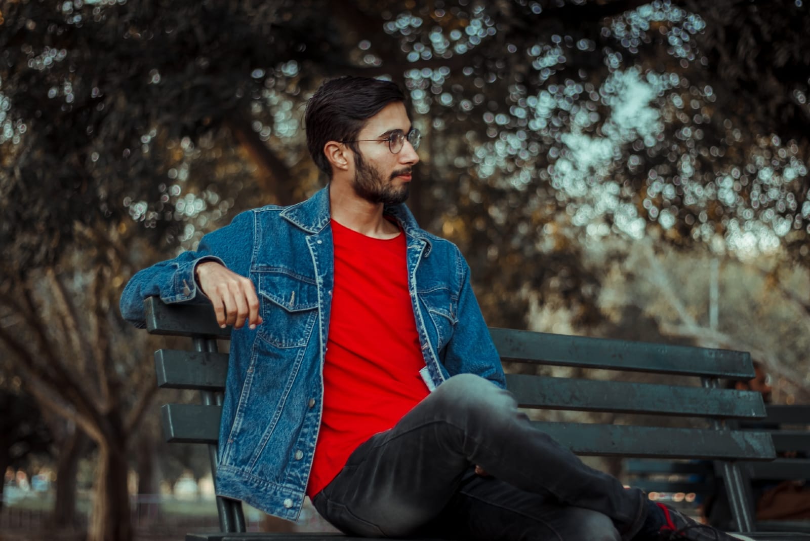 man in denim jacket sitting on bench