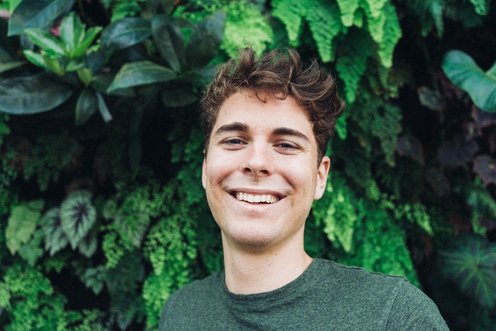man smiling while standing near plants