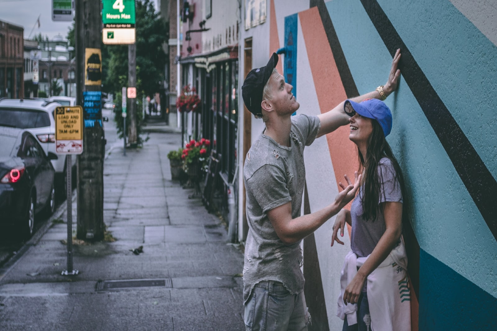 man talking to woman while standing near wall